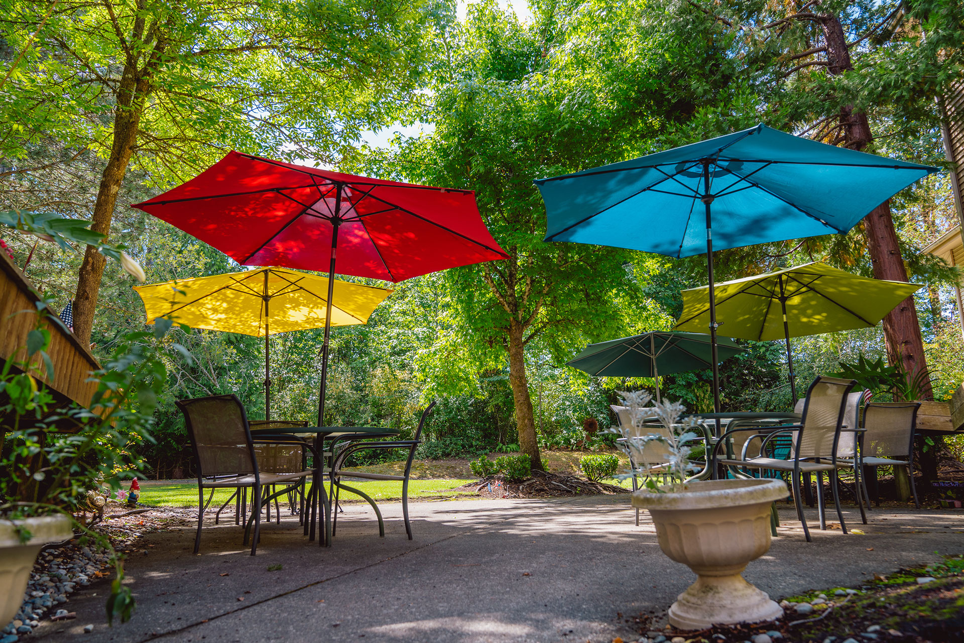A vibrant garden space with colorful umbrellas and outdoor seating under lush greenery.